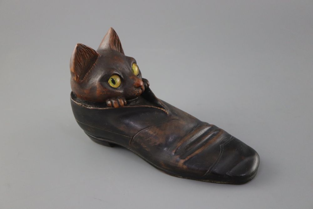 An early 20th century carved wood cat in a shoe inkwell, with hidden compartments, length 20cm